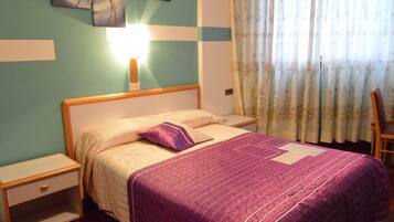 Un dormitorio con cama, mesitas de noche, lámpara y una silla.