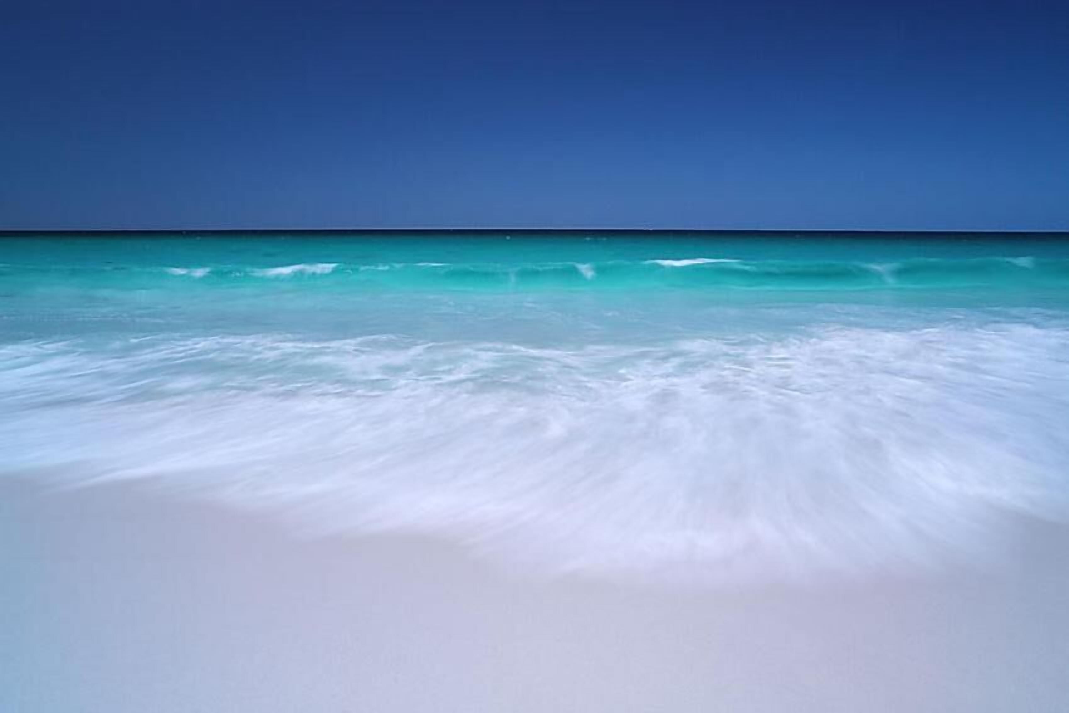 A beach with clear turquoise water and white sand.