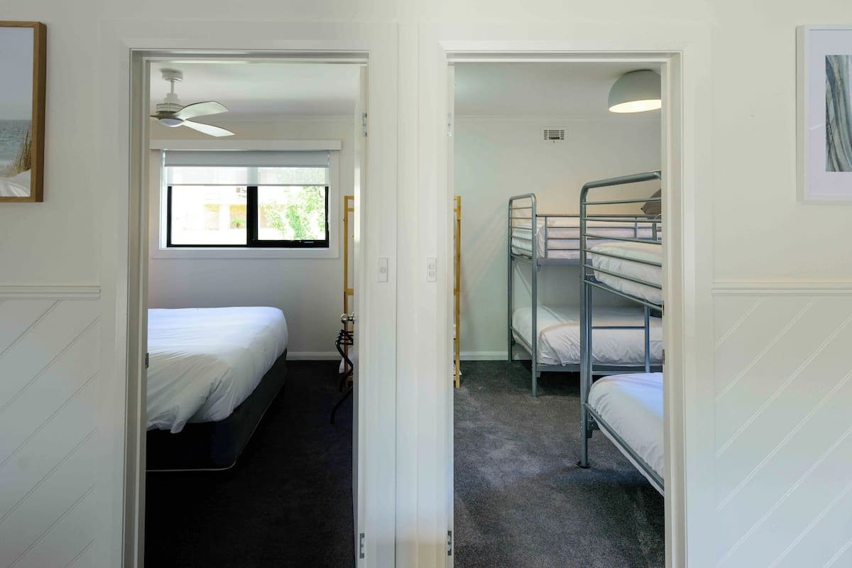 A room with a single bed, a window, and a bunk bed.