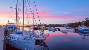 Una marina con varias embarcaciones amarradas en aguas tranquilas durante el atardecer.