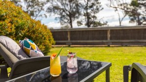 Una silla de descanso con cojín y una mesita de vidrio con dos bebidas.