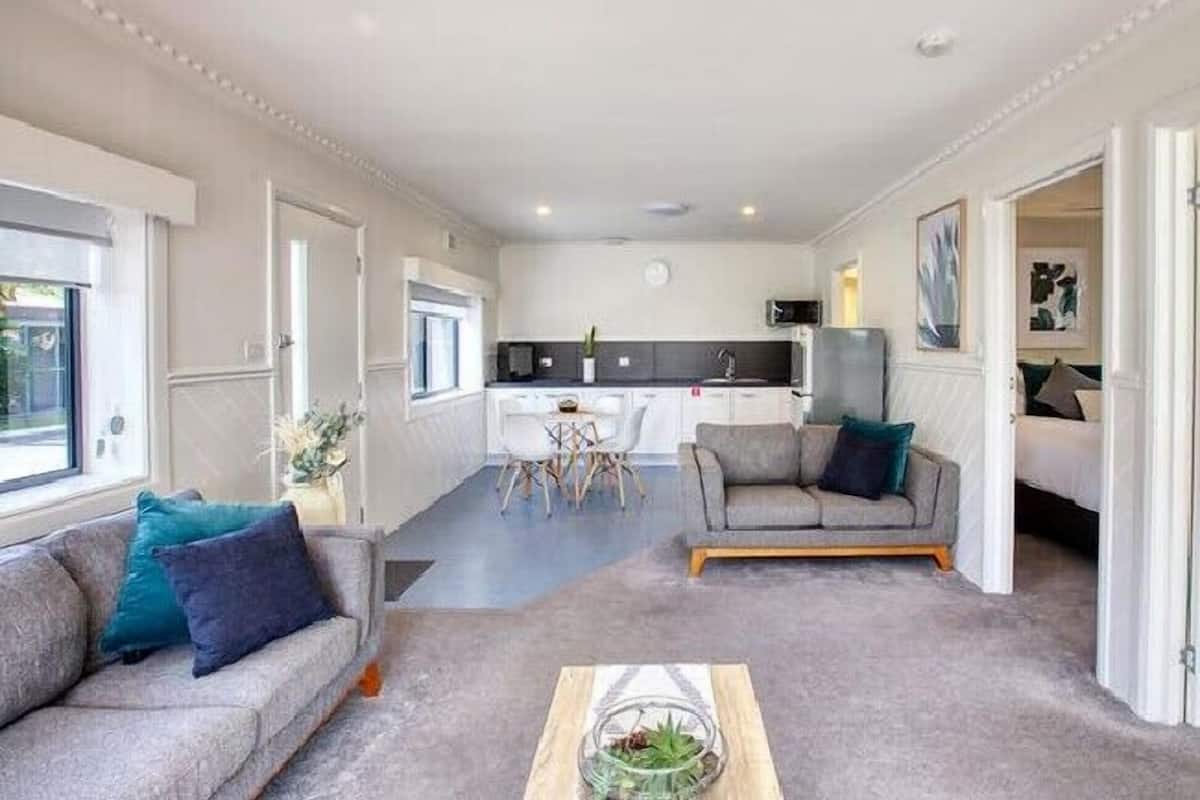 A compact living space with a kitchenette, a dining area, and a seating area with a sofa and armchair.