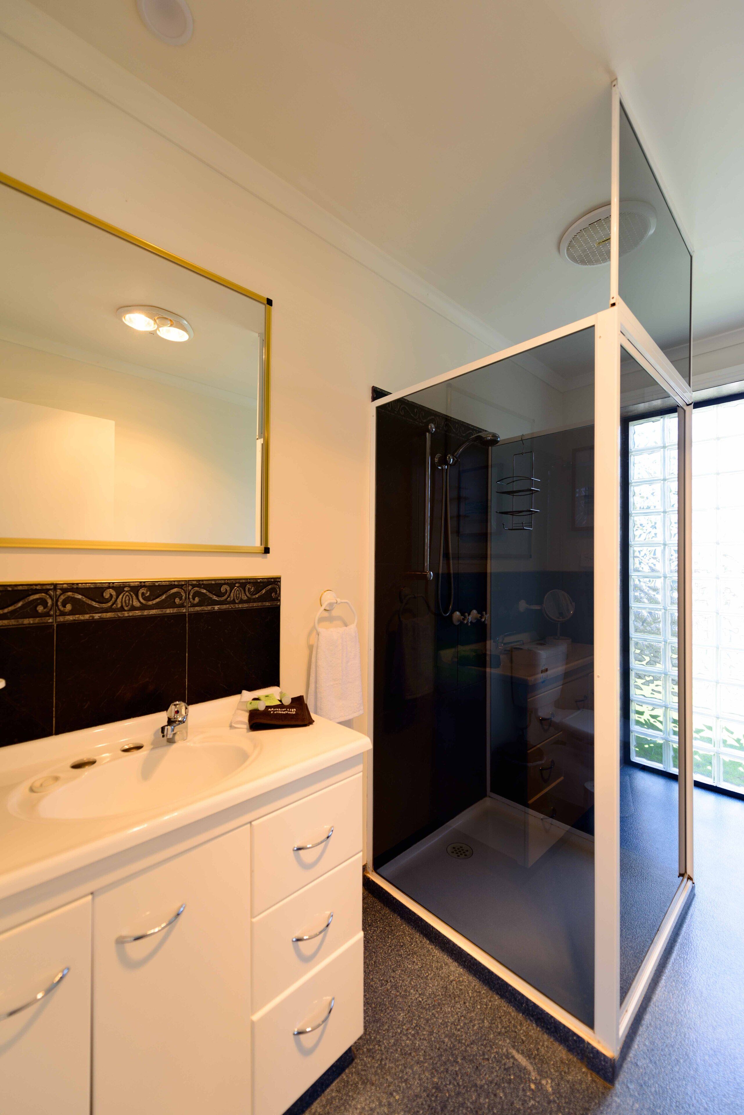Een moderne badkamer met twee wasbakken, een grote spiegel en een douche met glazen wanden.