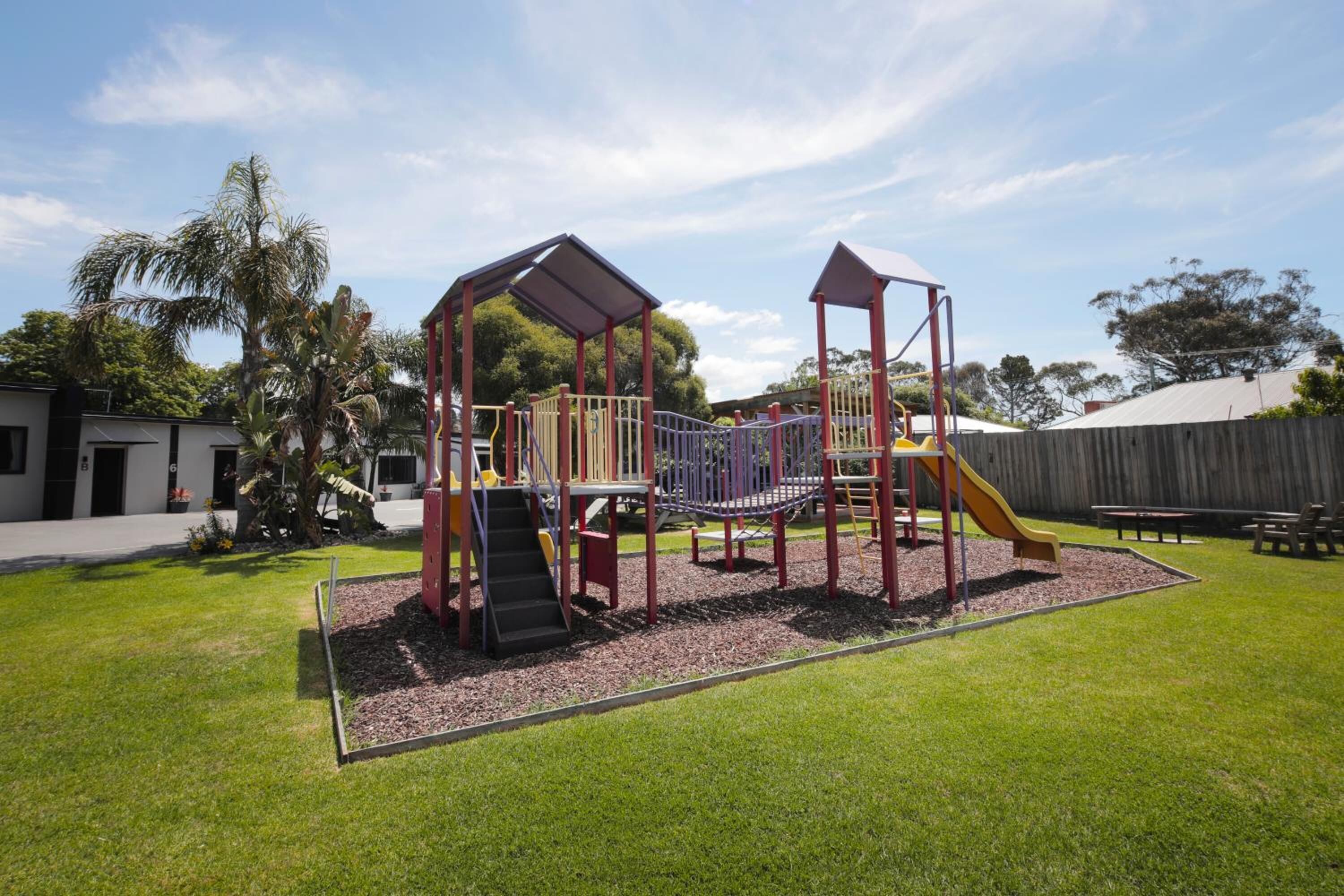 A playground with a slide, climbing structures, and a covered area.