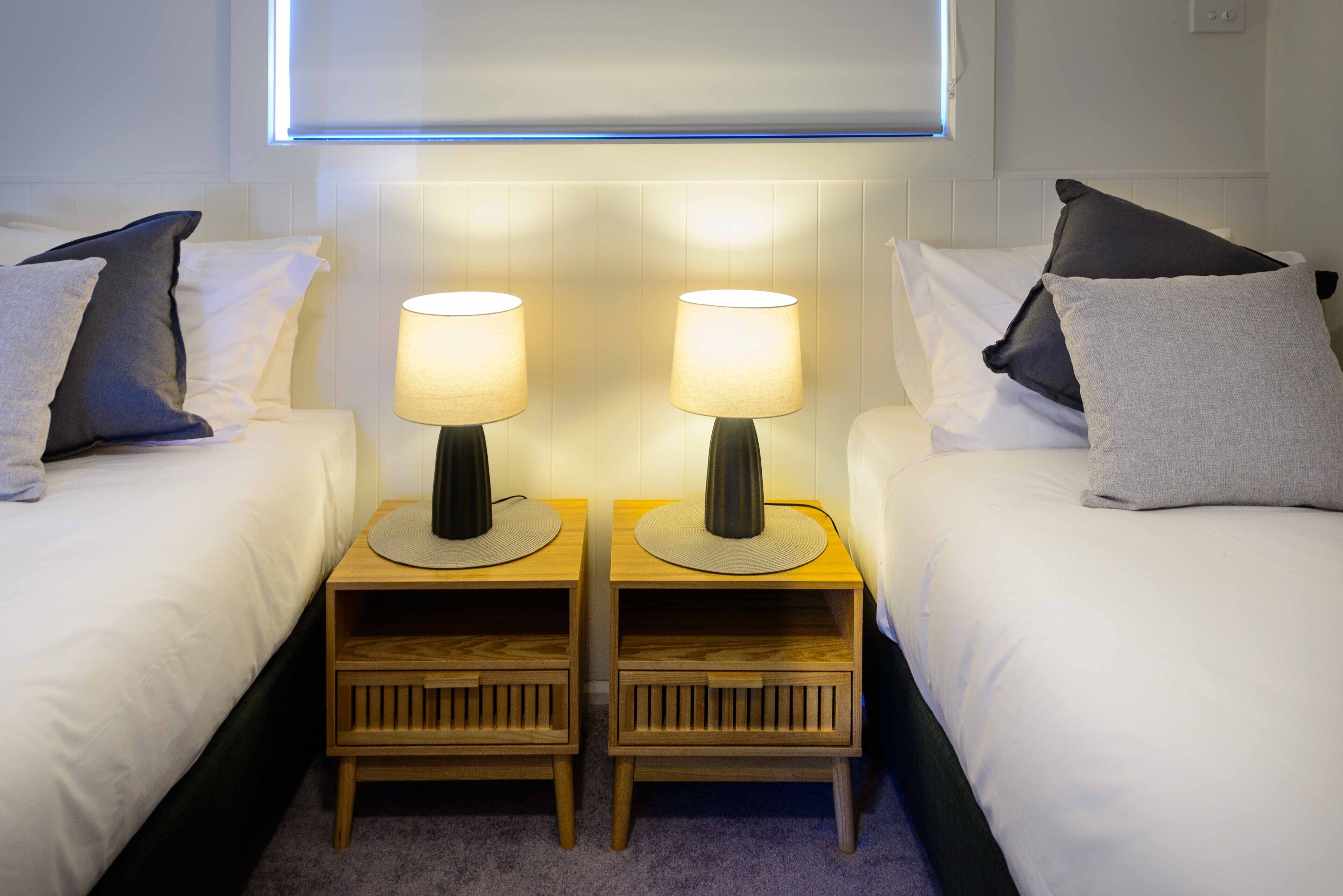 Ein Hotelzimmer mit zwei Betten, jeweils mit Nachttisch und Lampe.