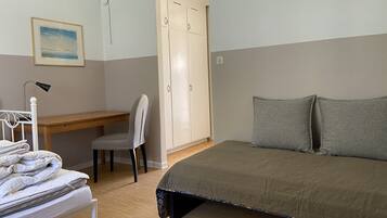 A bedroom with a bed, a desk, a chair, a wardrobe, and a bedside table.
