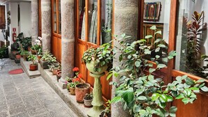 Ein Innenhof mit Steinsäulen, Holztüren und Kübelpflanzen.