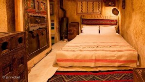 A traditional room with a bed, wooden furniture, and patterned textiles. - Dar KamalChaoui (Bhalil)