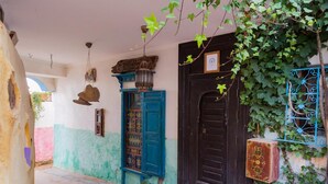 A traditional building with a black door, a blue door, and a small window. There is a sign on the door and a hanging lantern. - Dar KamalChaoui (Bhalil)