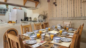 A dining area with a wooden table set for a meal, surrounded by chairs. - Dar KamalChaoui (Bhalil)