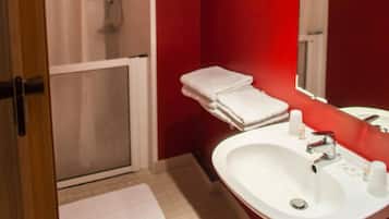 A bathroom with a white sink, a mirror, and a shower area.