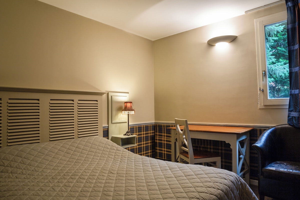 Une chambre à coucher avec un lit, un bureau, une chaise et une fenêtre avec des rideaux.