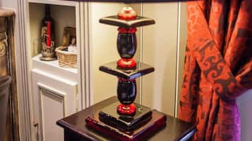 Een tafel met een zwarte lamp, een decoratief object en een klein plankje met boeken en een fles.