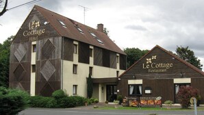 Een gebouw met twee verdiepingen, met een bord waarop 'Le Cottage Hotel' en 'Le Cottage Restaurant' staat.