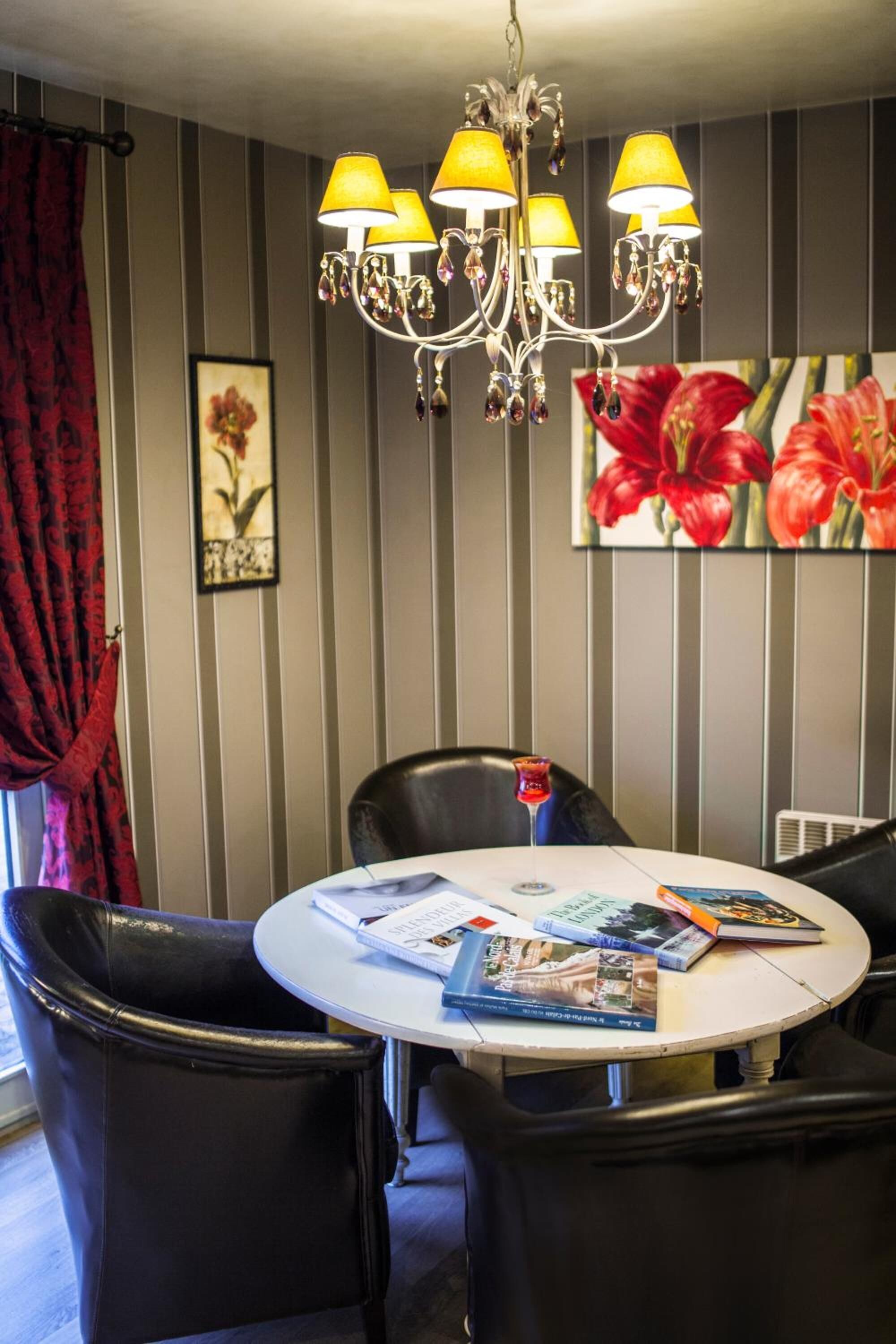 A dining area with a round table, black chairs, and a chandelier with multiple lamps.
