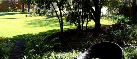 A garden with a wooden deck, a chair, and a lawn.