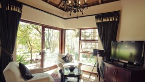 A living room with a TV, a glass coffee table, and a sofa. - Lourie Lodge (Sandton)