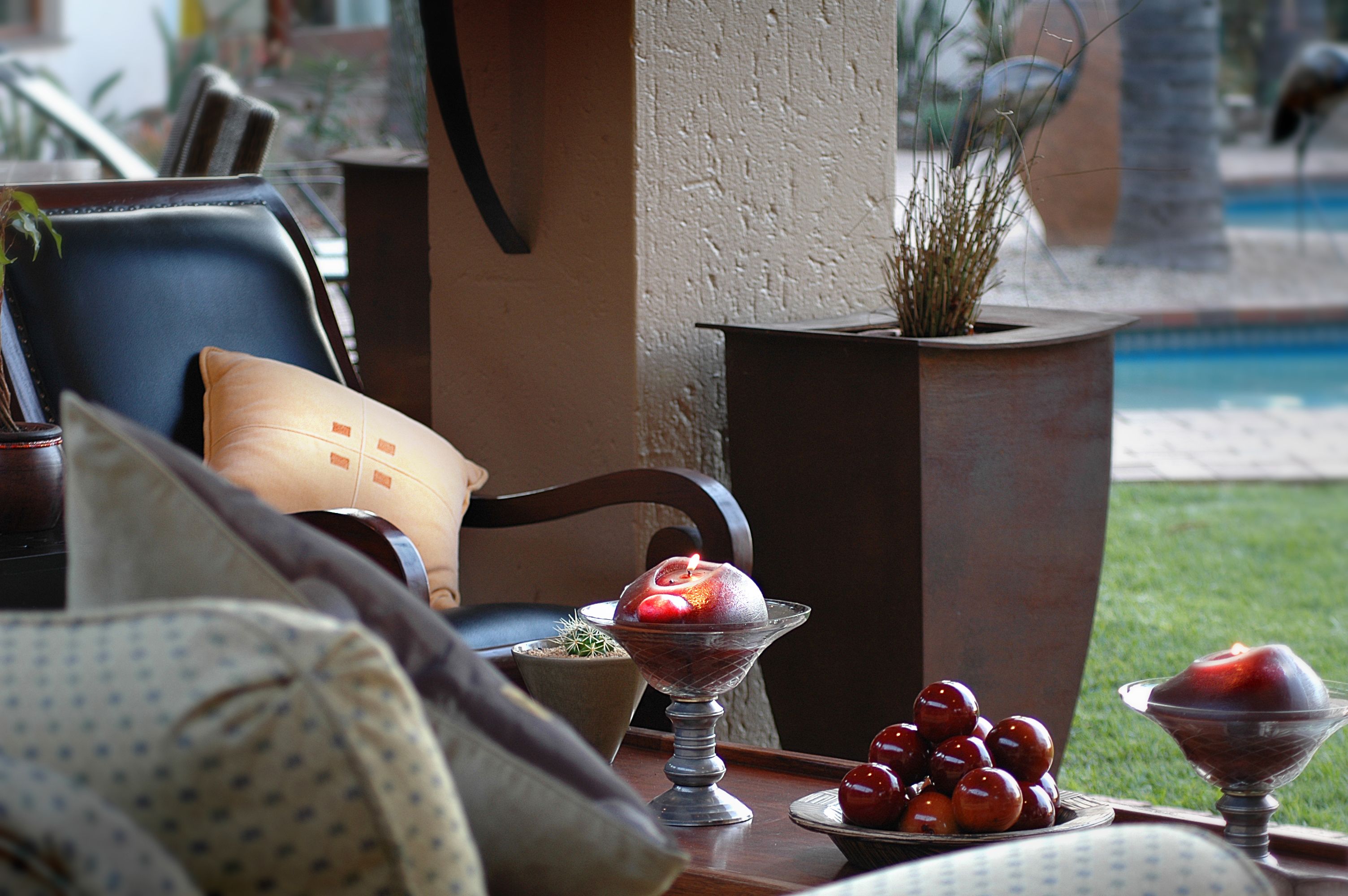 A dining table with a glass bowl of fruit, a potted plant, and a chair with a cushion.