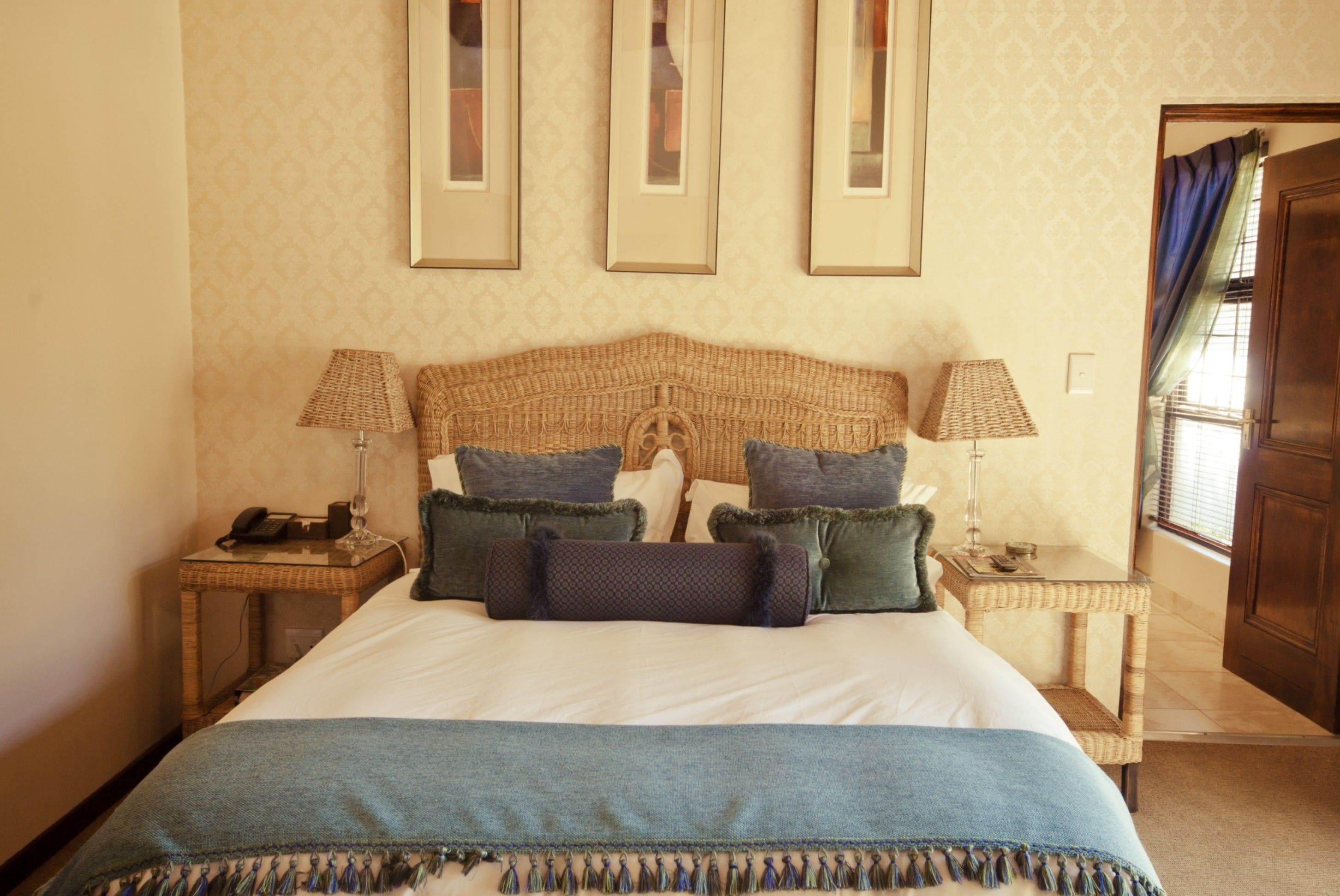 A neatly arranged hotel room with a large bed, two bedside tables with lamps, a telephone, and framed pictures on the wall.