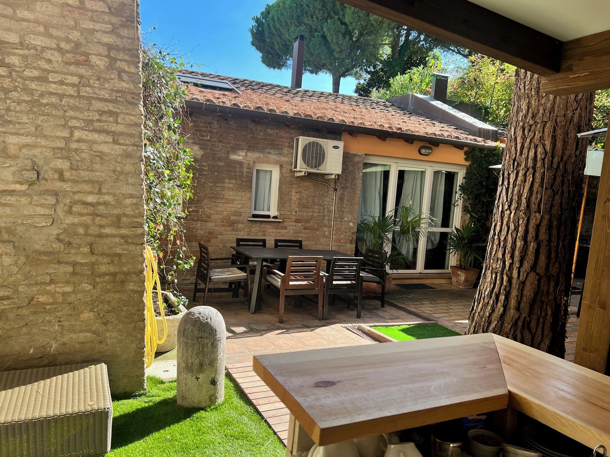 Eine Terrasse mit Tisch und Stühlen, einer Steinsäule und einer Backsteinmauer.