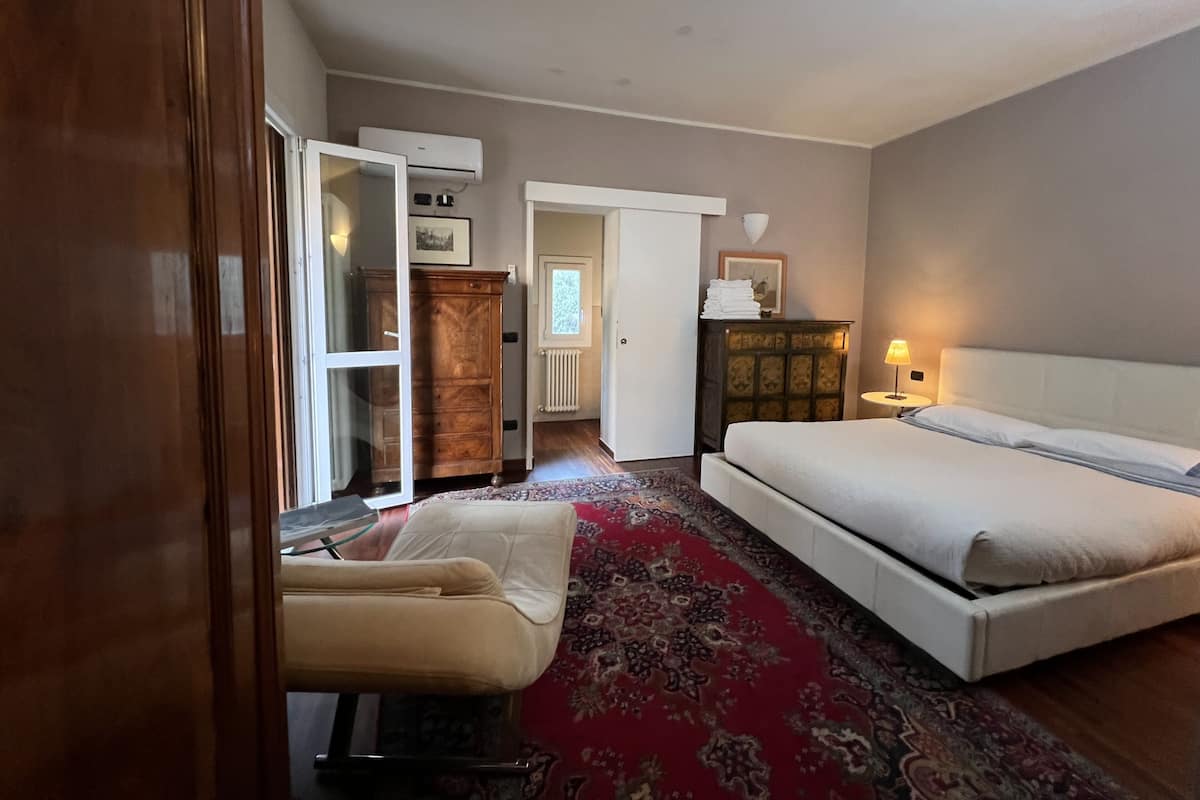 A bedroom with a bed, a chair, a wardrobe, and a radiator.