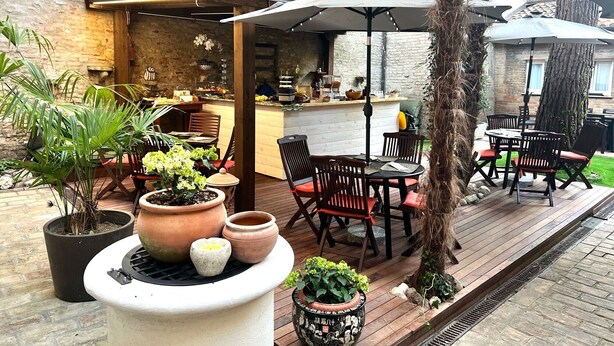 Een terras buiten met houten vloer, een bar en zitgedeeltes.