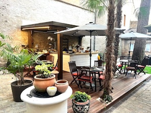 Un espace extérieur aménagé en terrasse, avec un sol en bois, un comptoir de bar et des sièges.