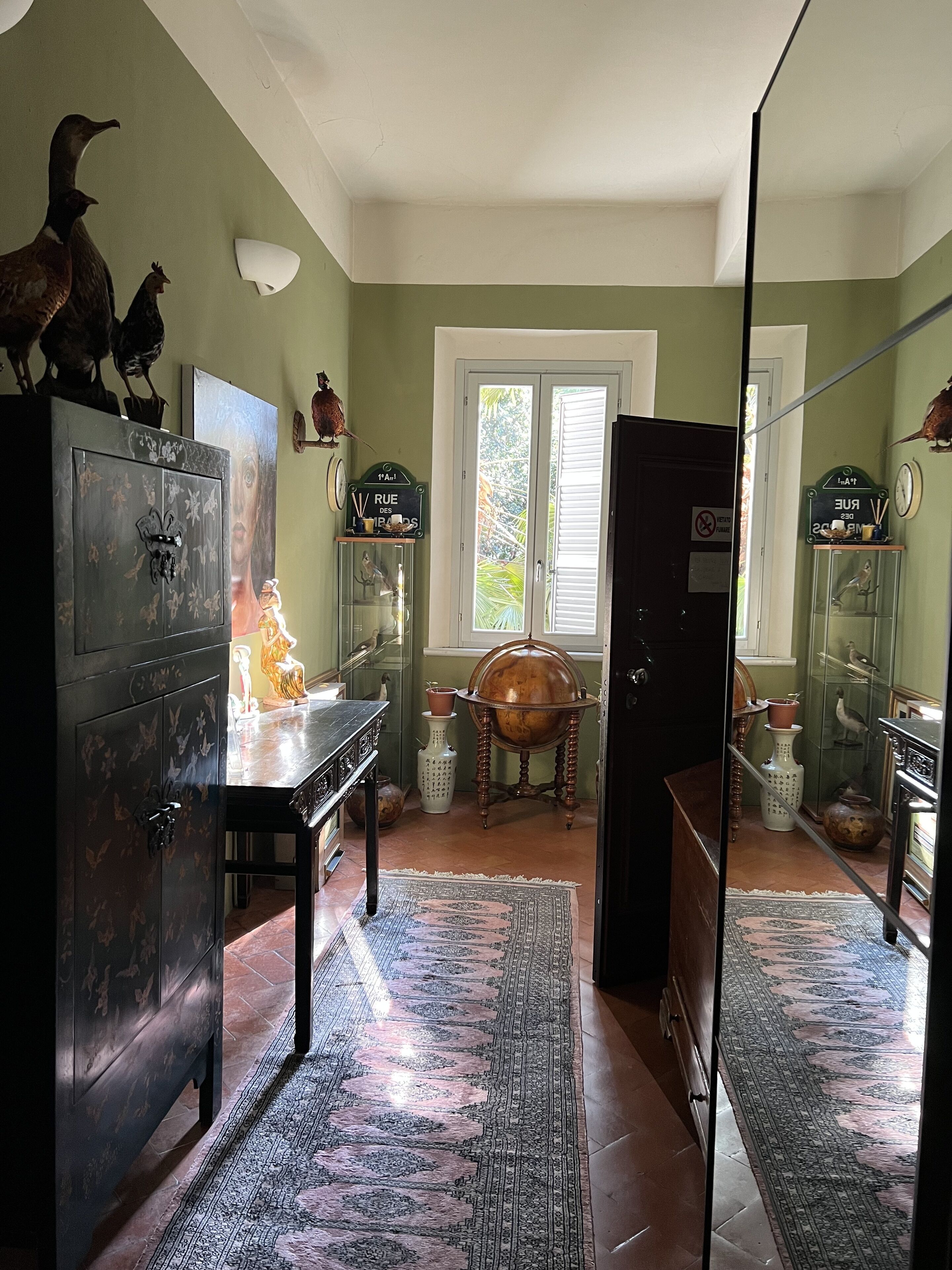 Una habitación con un armario grande, una mesa, un tapete y una ventana con persianas.
