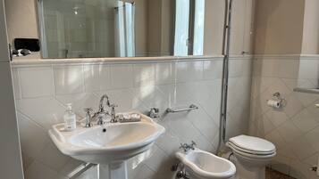 Une salle de bain équipée d’un lavabo, d’un bidet, de toilettes et d’une douche.