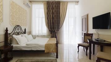 A bedroom with a bed, bedside table, chair, TV, and curtains.