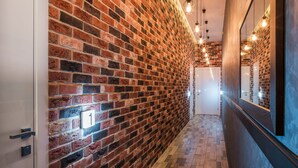 Un couloir avec un mur en briques, un plancher en bois et une porte portant un numéro.