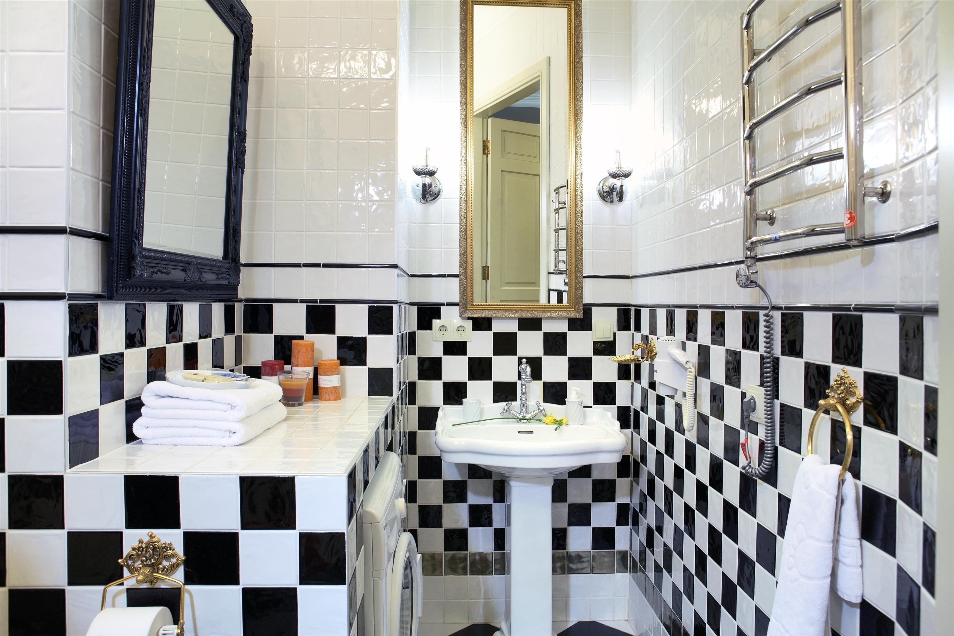 Ein Badezimmer mit Schachbrettmuster in Schwarz und Weiß, einem weißen Waschbecken, einem Spiegel und einem Handtuchhalter.