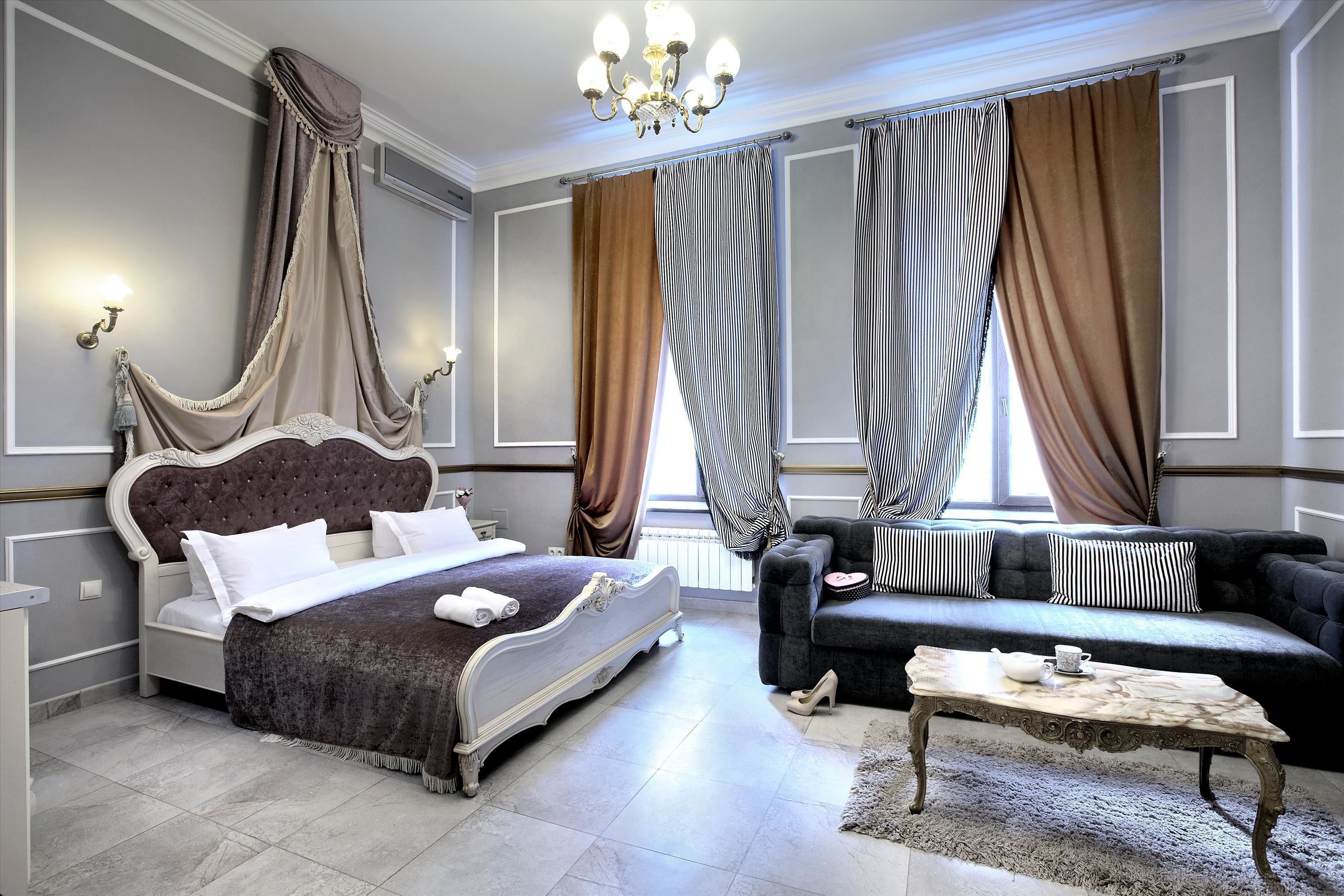 Une chambre à coucher avec un grand lit, un canapé, une table basse et des rideaux.