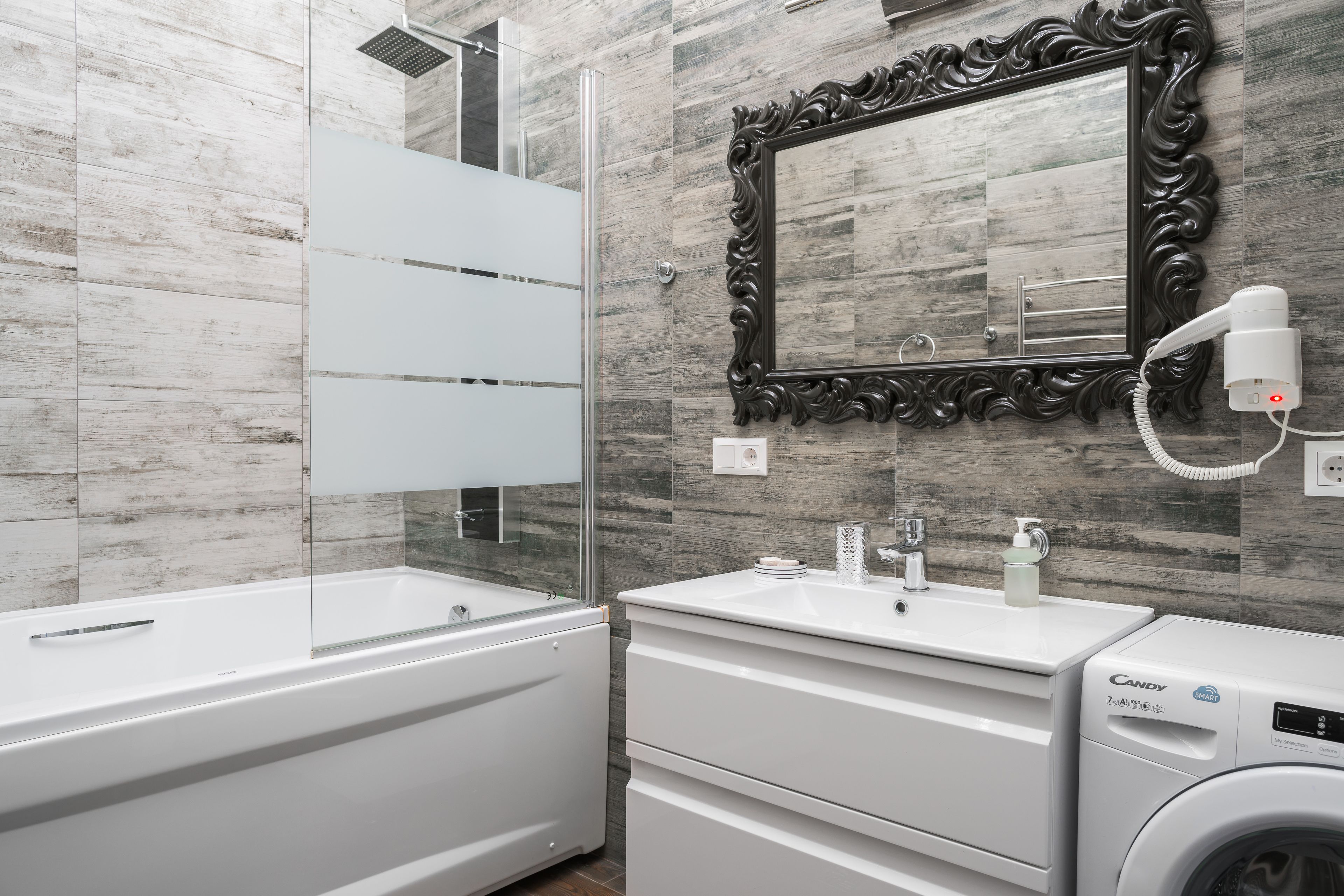 A modern bathroom with a bathtub, a vanity with a mirror, and a washing machine.