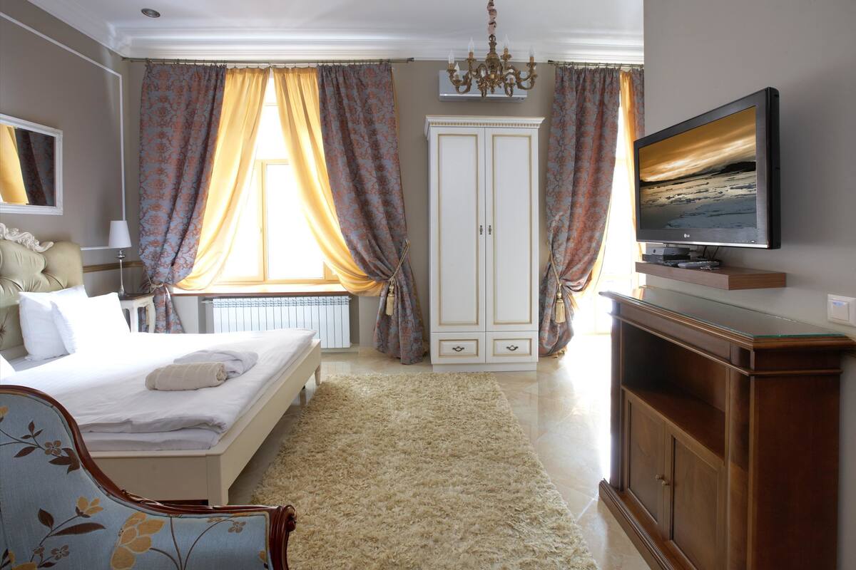 Un dormitorio con cama, televisión, armario y candelabro.