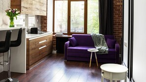 Une cuisine moderne avec des meubles en bois, un coin repas doté d’un canapé violet et une table ronde blanche.