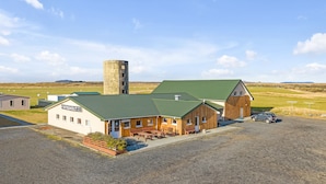 A reception building with a green roof, a tall cylindrical tower, and a parking area with a car.