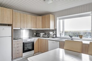 A modern kitchen with wooden cabinets, a stainless steel range, a dishwasher, and a window overlooking a scenic view.