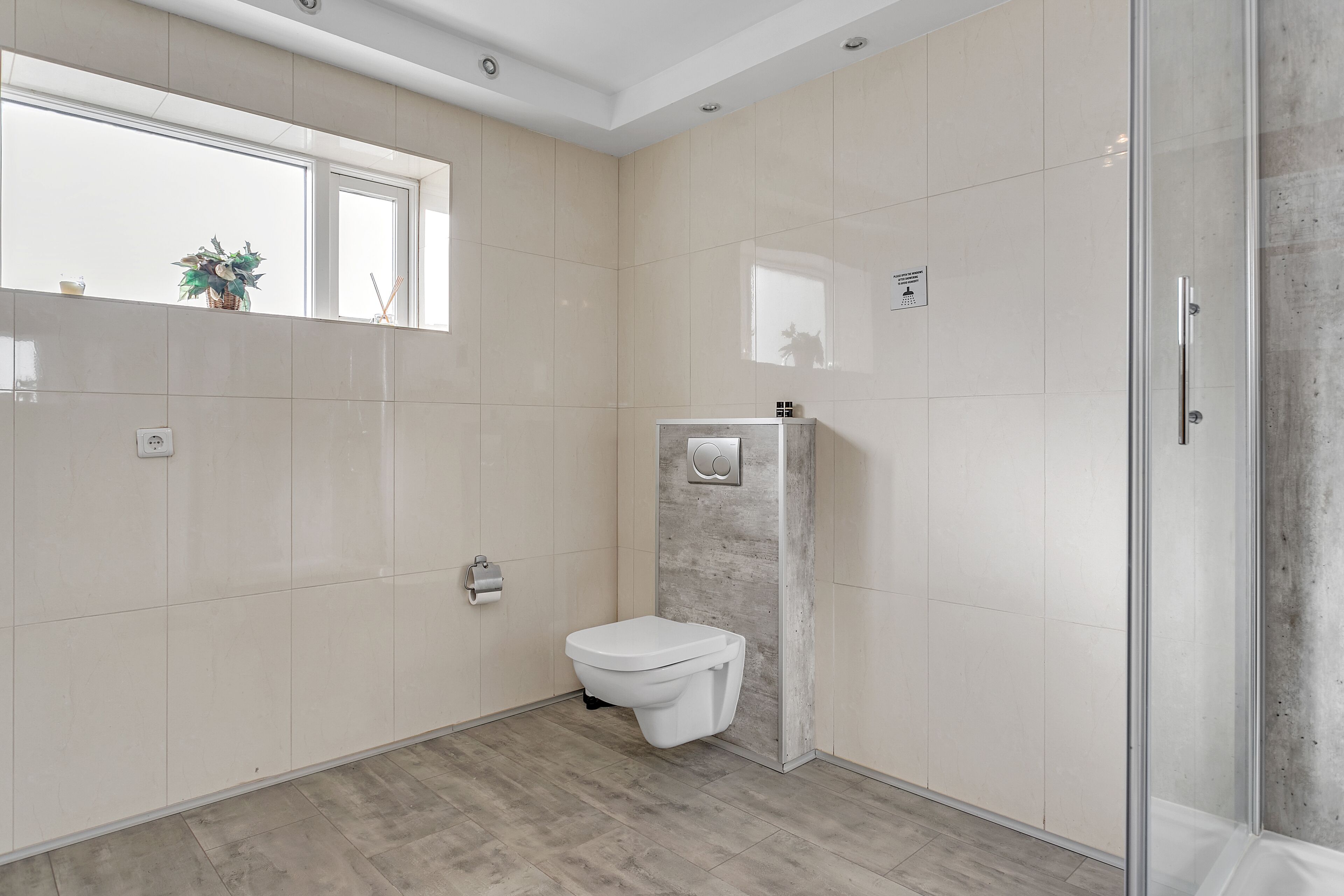 Un baño moderno con inodoro, cabina de ducha y ventana.