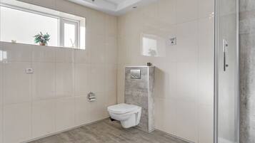 Un baño moderno con inodoro, cabina de ducha y ventana.
