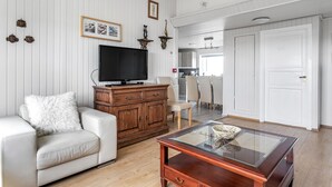 A living room with a sofa, a television, a wooden cabinet, and a glass coffee table.