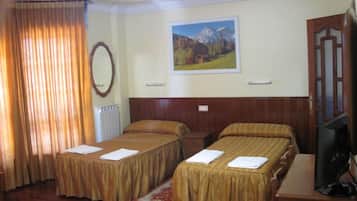 Camera d'albergo con due letti, una testiera in legno, un quadro che raffigura un paesaggio montano, uno specchio e un televisore su un mobile in legno.