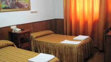 A hotel room with two beds, a nightstand, a telephone, and a painting of a horse on the wall.