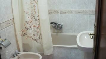 A bathroom with a toilet, bidet, bathtub, and sink.