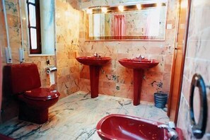 A bathroom with a red toilet, two red sinks, a bathtub, and a window. - Hotel Antoyana (Santander)