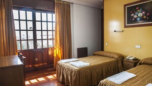 A hotel room with two beds, a wooden desk, a telephone, and a painting on the wall.
