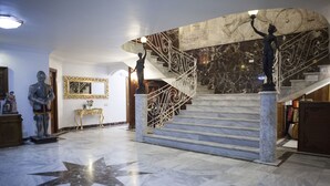 A grand lobby with marble floors, a star-shaped design, and a staircase with ornate railings.