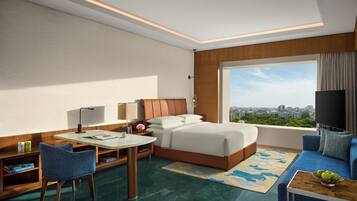 A hotel room with a bed, desk, chair, and a large window offering a city view.