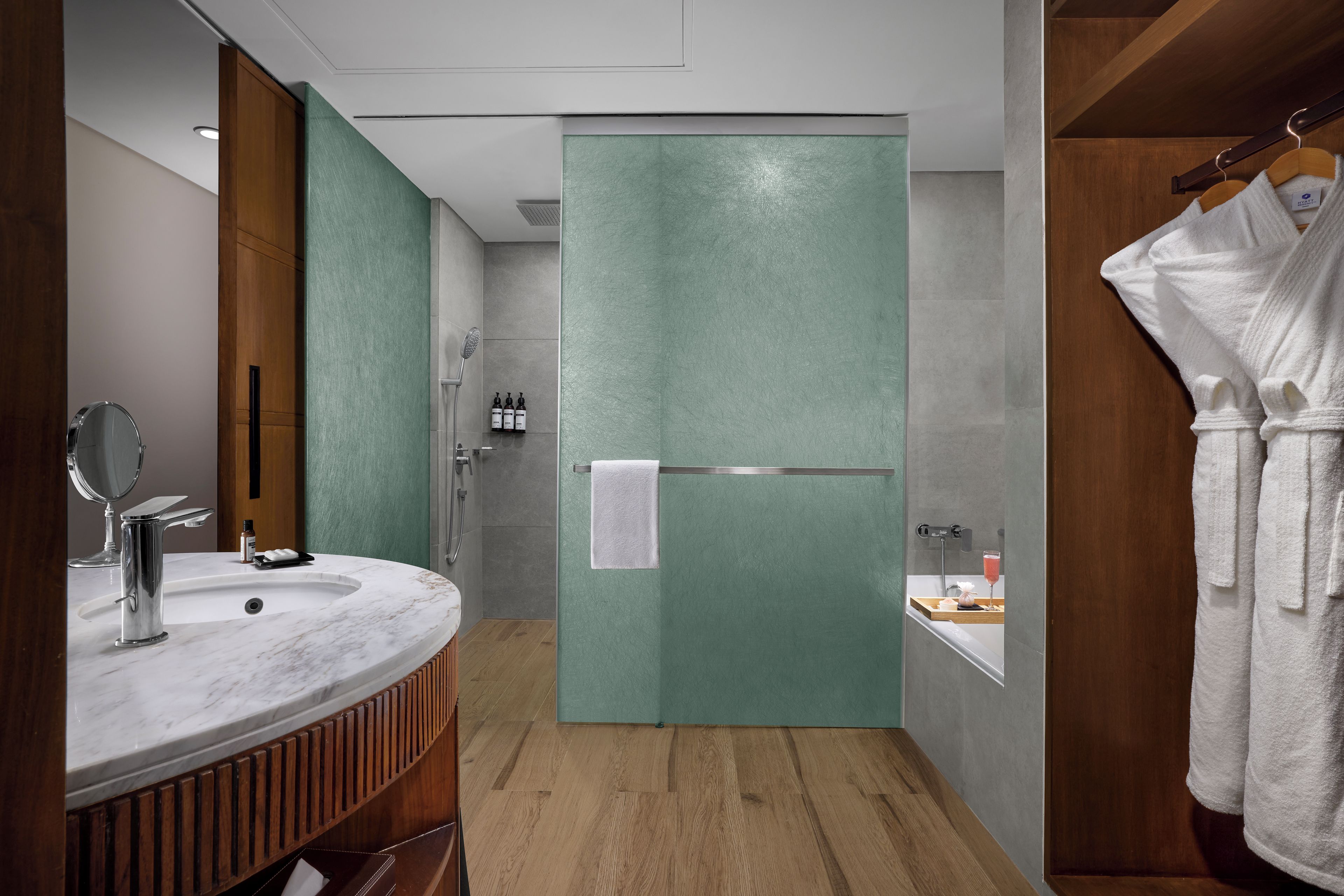 Ein modernes Badezimmer mit Marmorwaschbecken, einem Holzbadezimmermöbel, einer Glasdusche und einem weißen Handtuchhalter.