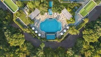 Vista aérea de um resort com uma piscina central, rodeado por áreas ajardinadas e vários edifícios.